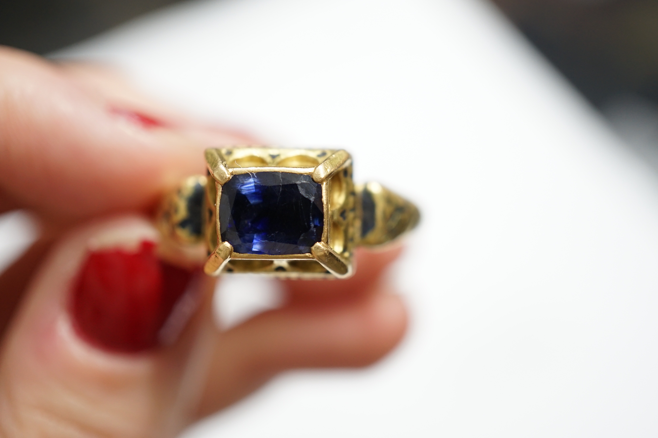 An antique high carat gold, black enamel and collet set cushion cut sapphire set 'poison' ring